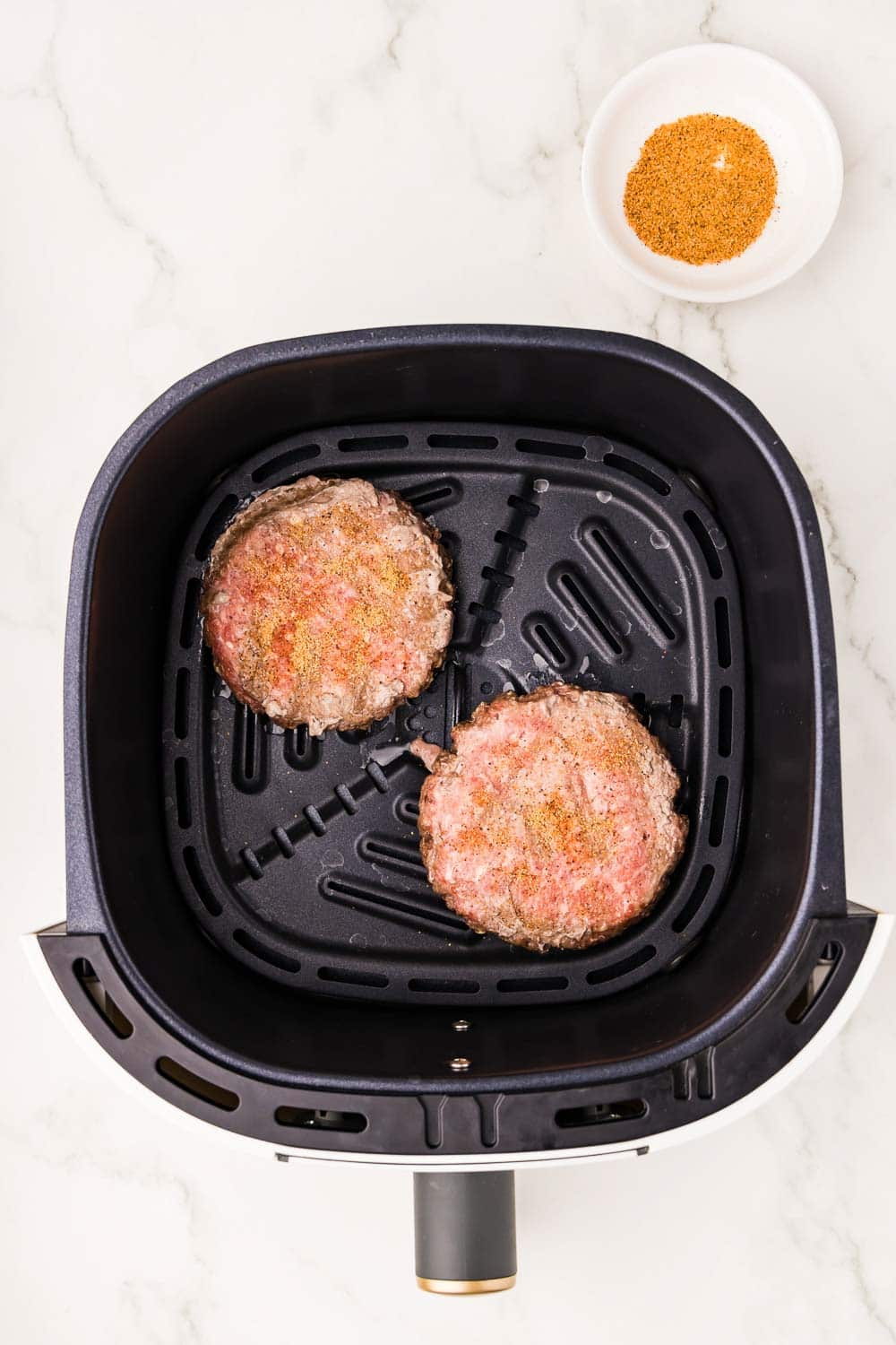 2 burger patties in the process of being cooked in air fryer