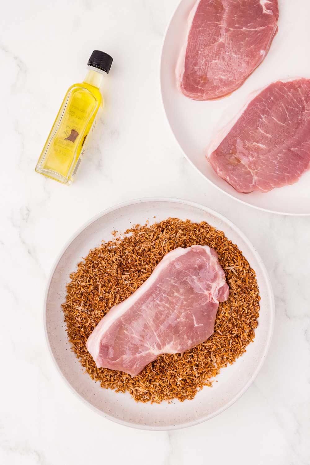 Uncooked pork chop laid on a bed of seasoning