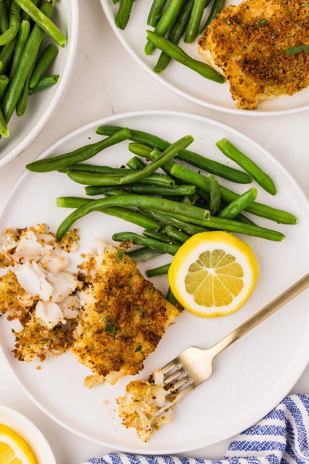 Close up of Air Fryer Cod with form next to lemon slice and green beans