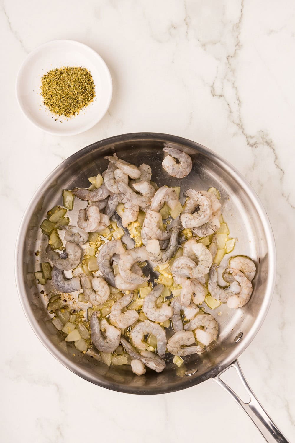 In a 12 inch skillet heat olive oil and onion and garlic and simmering until onion starts to soften shrimp added in