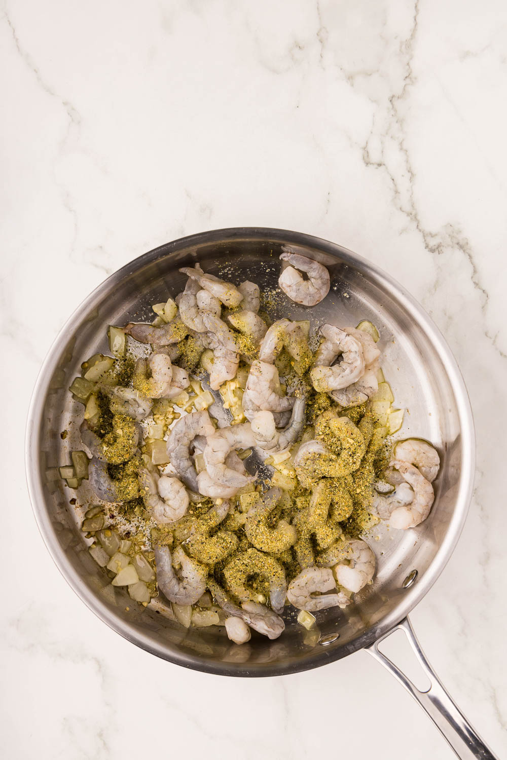 Skillet with onion, garlic, shrimp and herb seasoning simmering