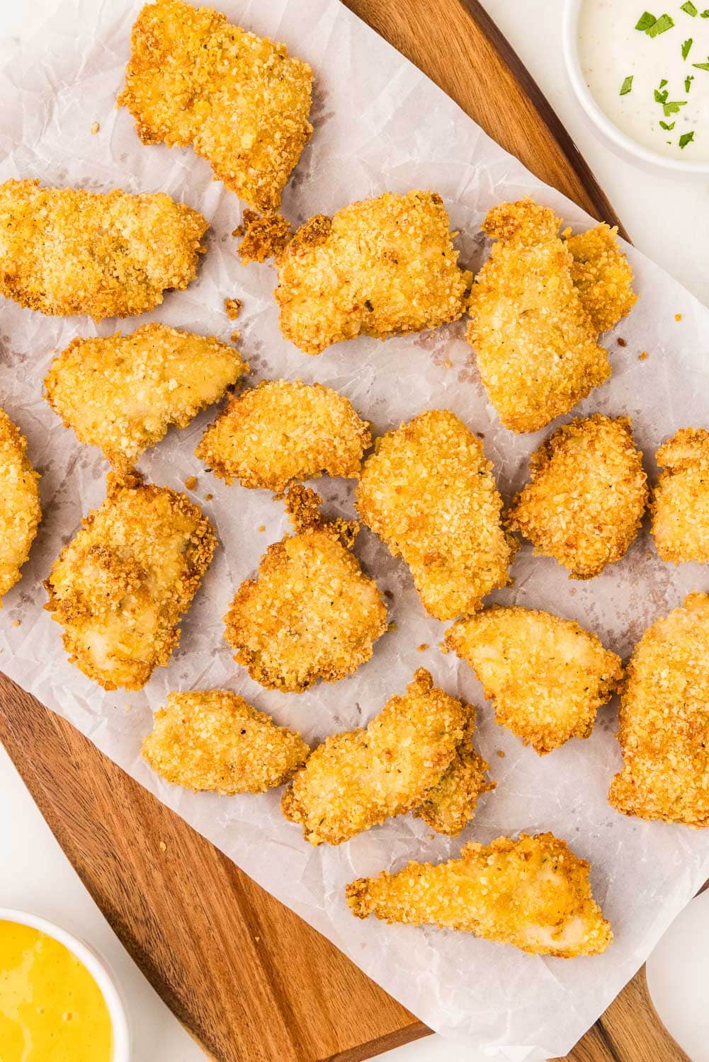 Air Fryer Chicken Nuggets on parchment paper and wooden cutting board