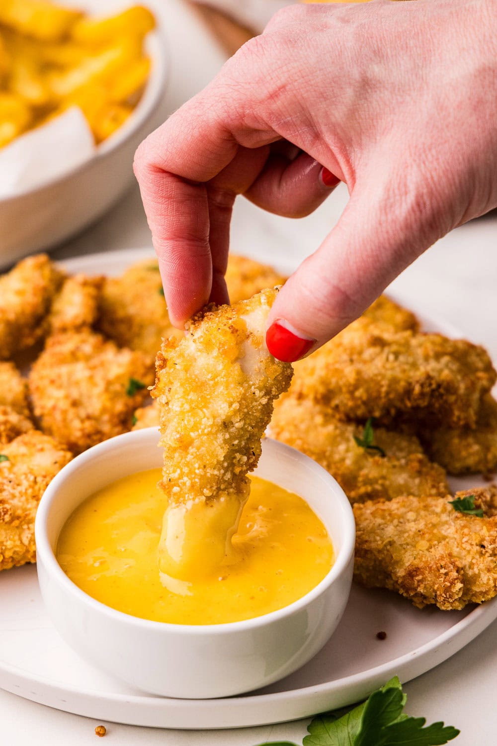 Air Fryer Chicken Nuggets being dipped into honey mustard ready to eat