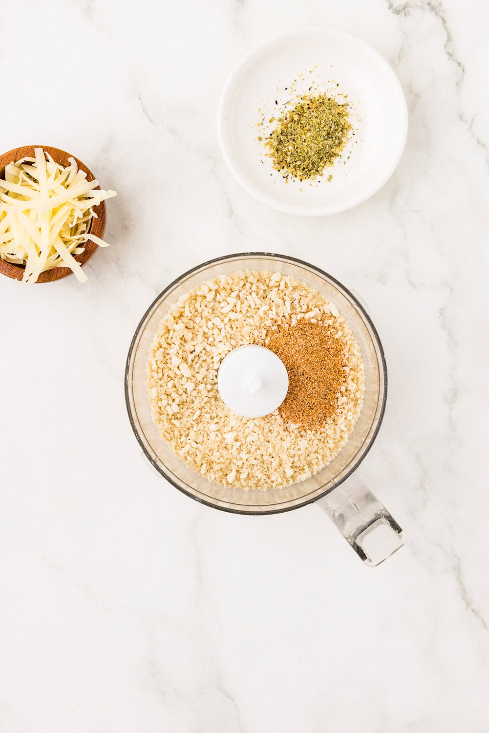 Blender with breading and seasoning next to cheese and seasonings