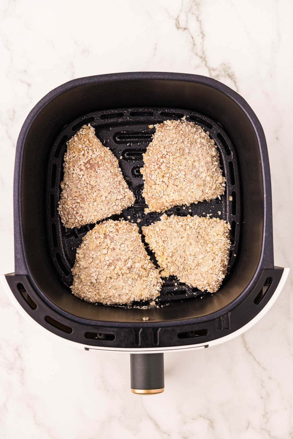 Air fryer basket with cooking spray with chicken in basket it a single layer not overlapping