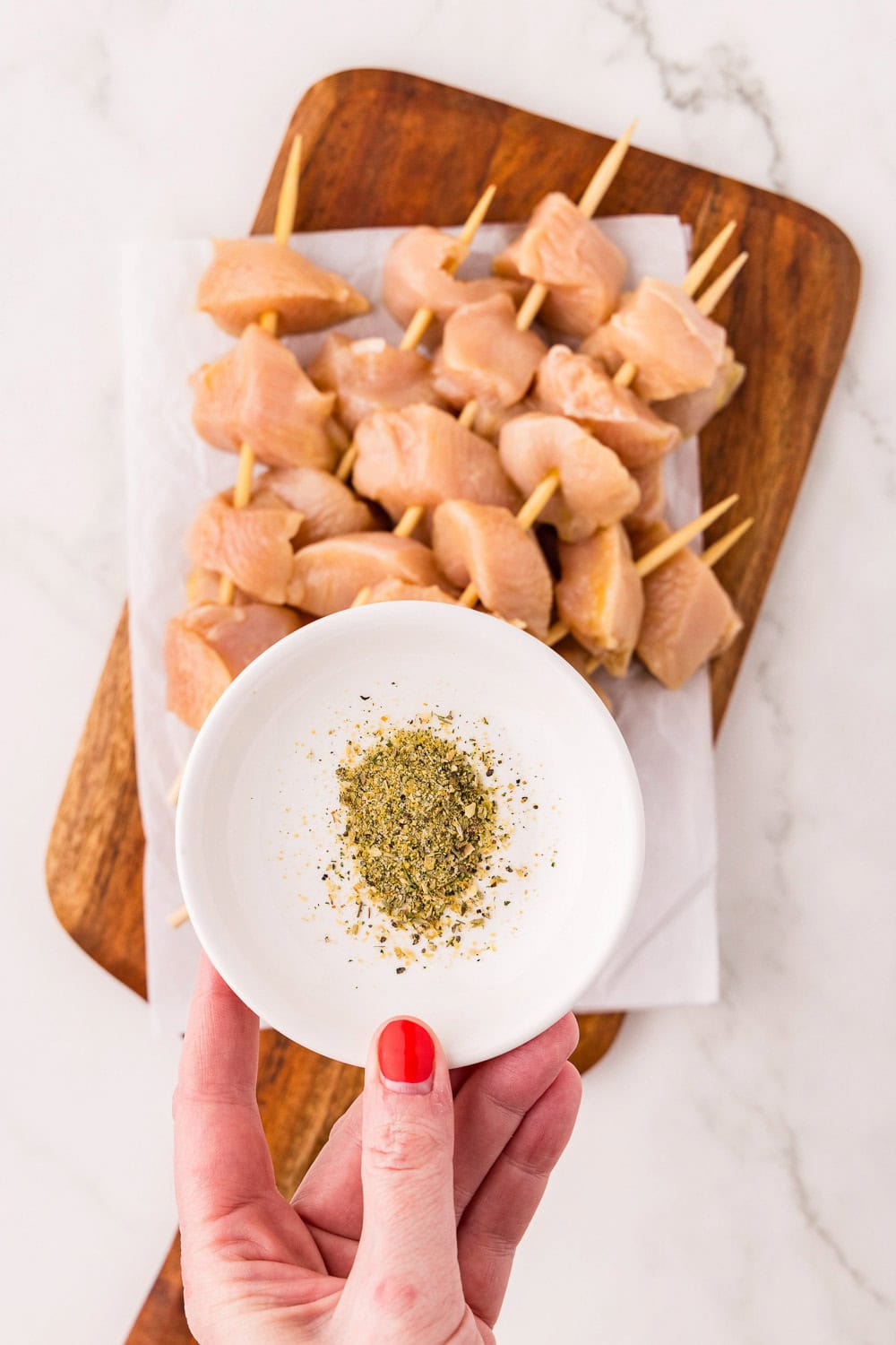 Raw Herb Marinated Air Fryer Chicken Skewers on cutting board with a small plate of seasonings on top
