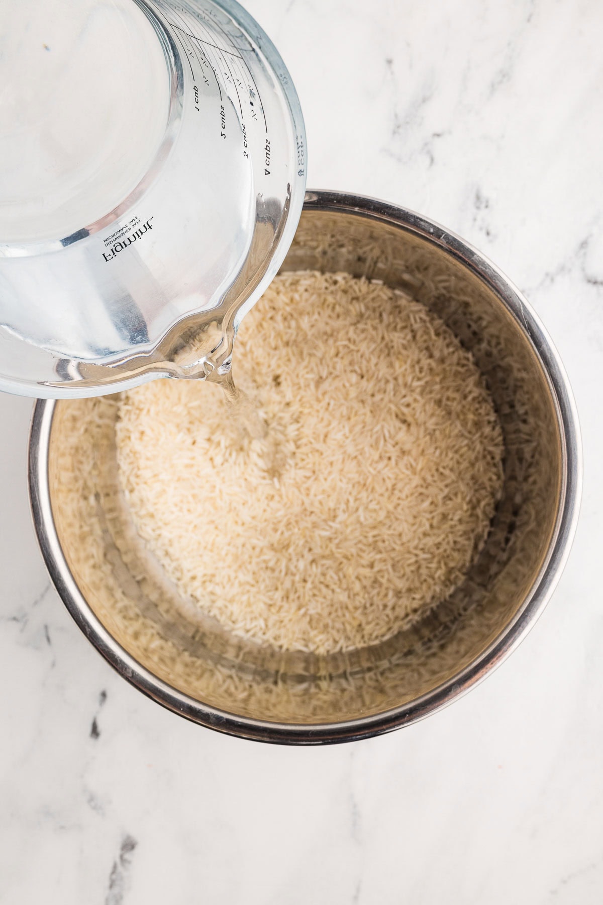 Water being added to bowl of uncooked basmati rice