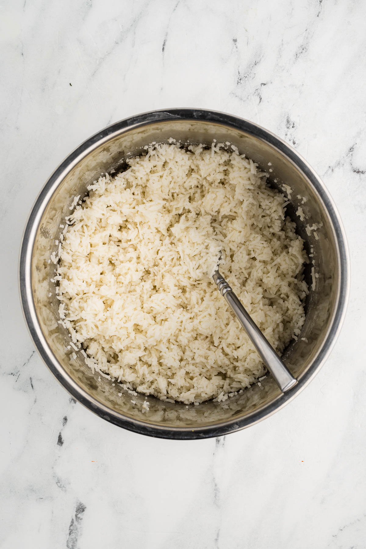 Bowl of basmati rice being fluffed with fork