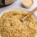 white plate of cooked quinoa next to instant pot