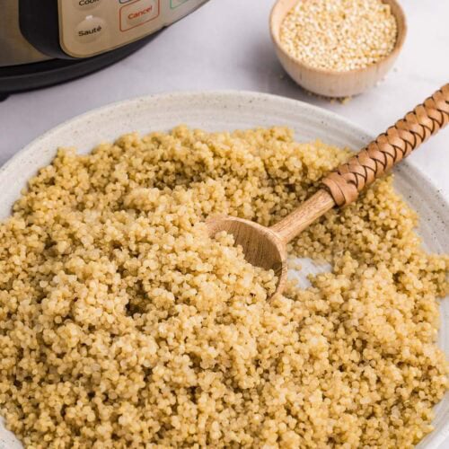 white plate of cooked quinoa next to instant pot