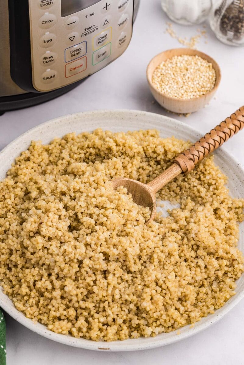 white plate of cooked quinoa next to instant pot