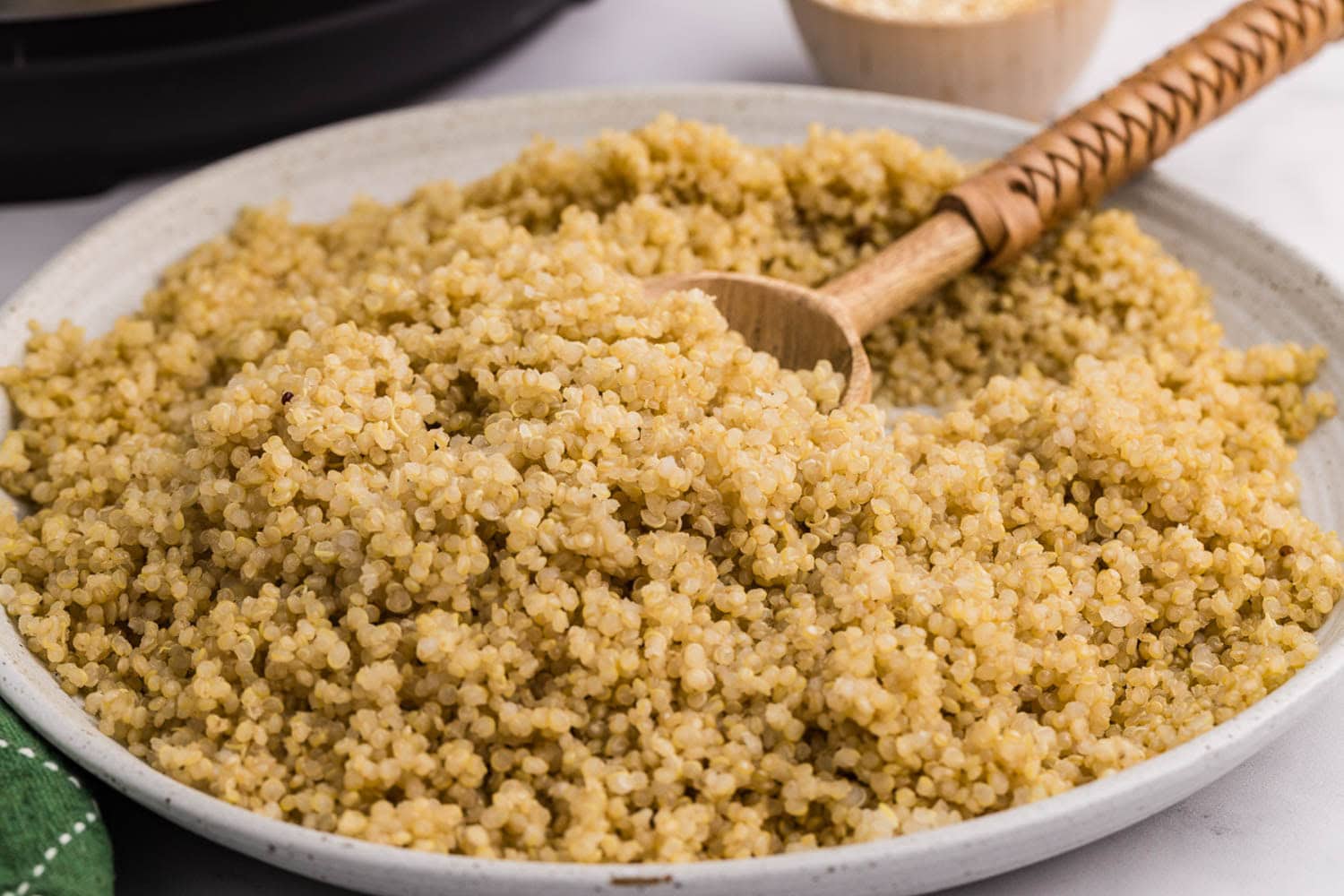 white plate of quinoa with wood spoon