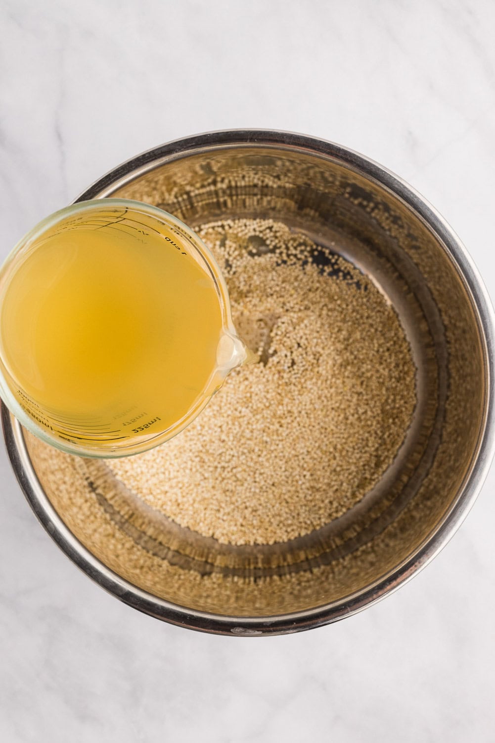 chicken broth being poured over quinoa in instant pot