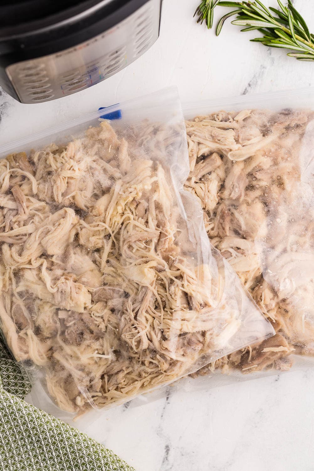 two plastic storage baggies of shredded chicken next to instant pot