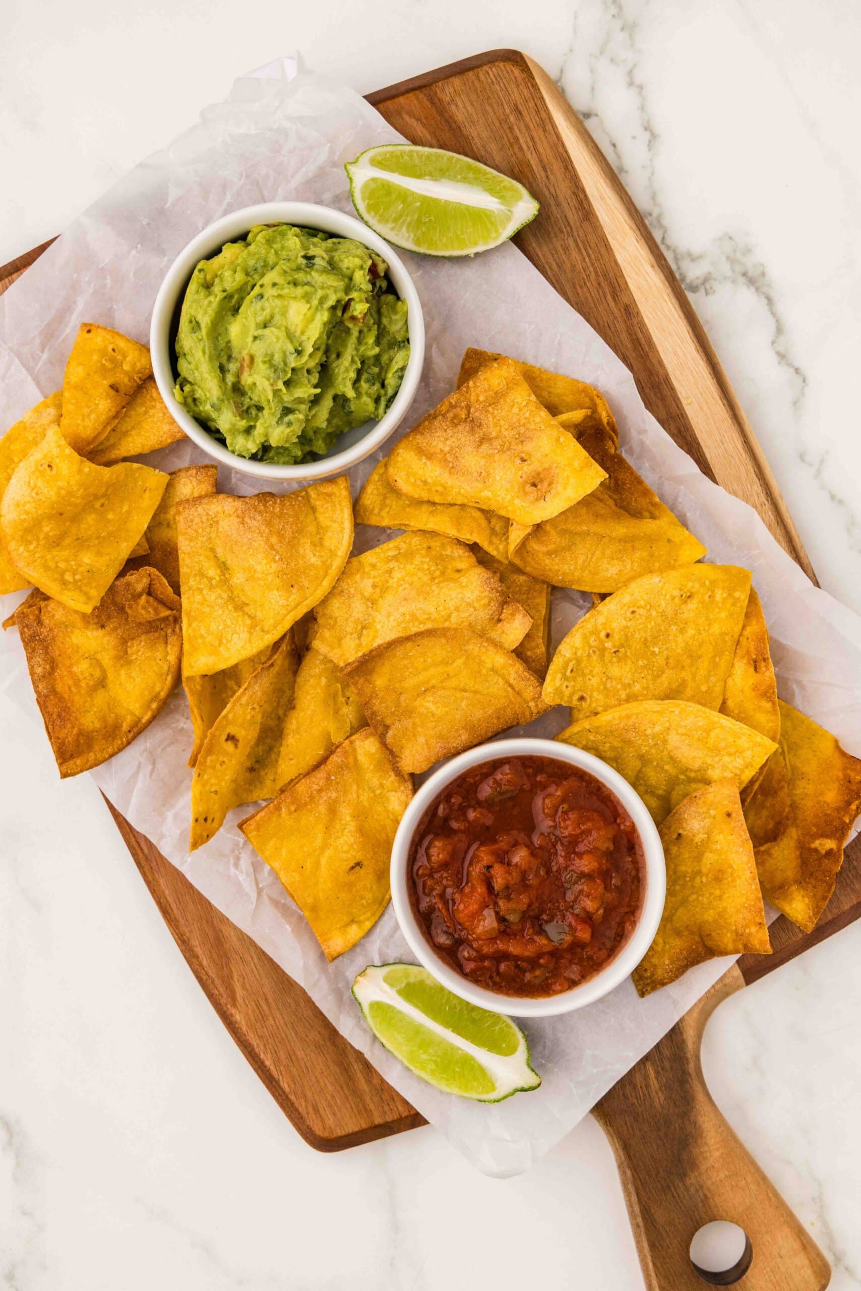 platter of tortilla chips and salsa, guacamole, and lime wedges