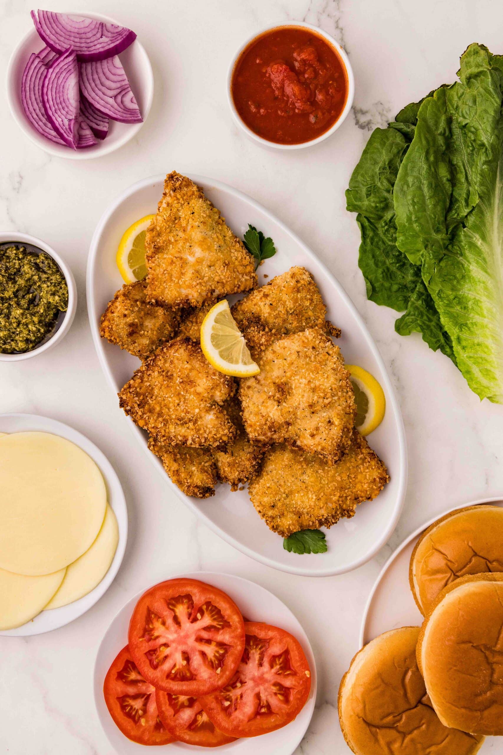 4 Crispy Air Fryer Chicken Cutlets
4 burger buns (brioche or ciabatta work well)
4 slices provolone cheese
½ cup marinara sauce
¼ cup pesto sauce
Lettuce, tomato, and onions for topping