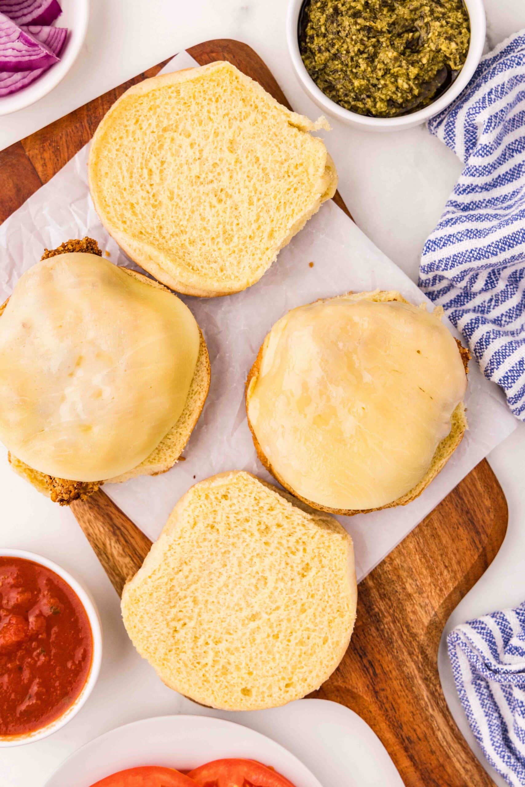Open buns on cutting board with slices of cheese