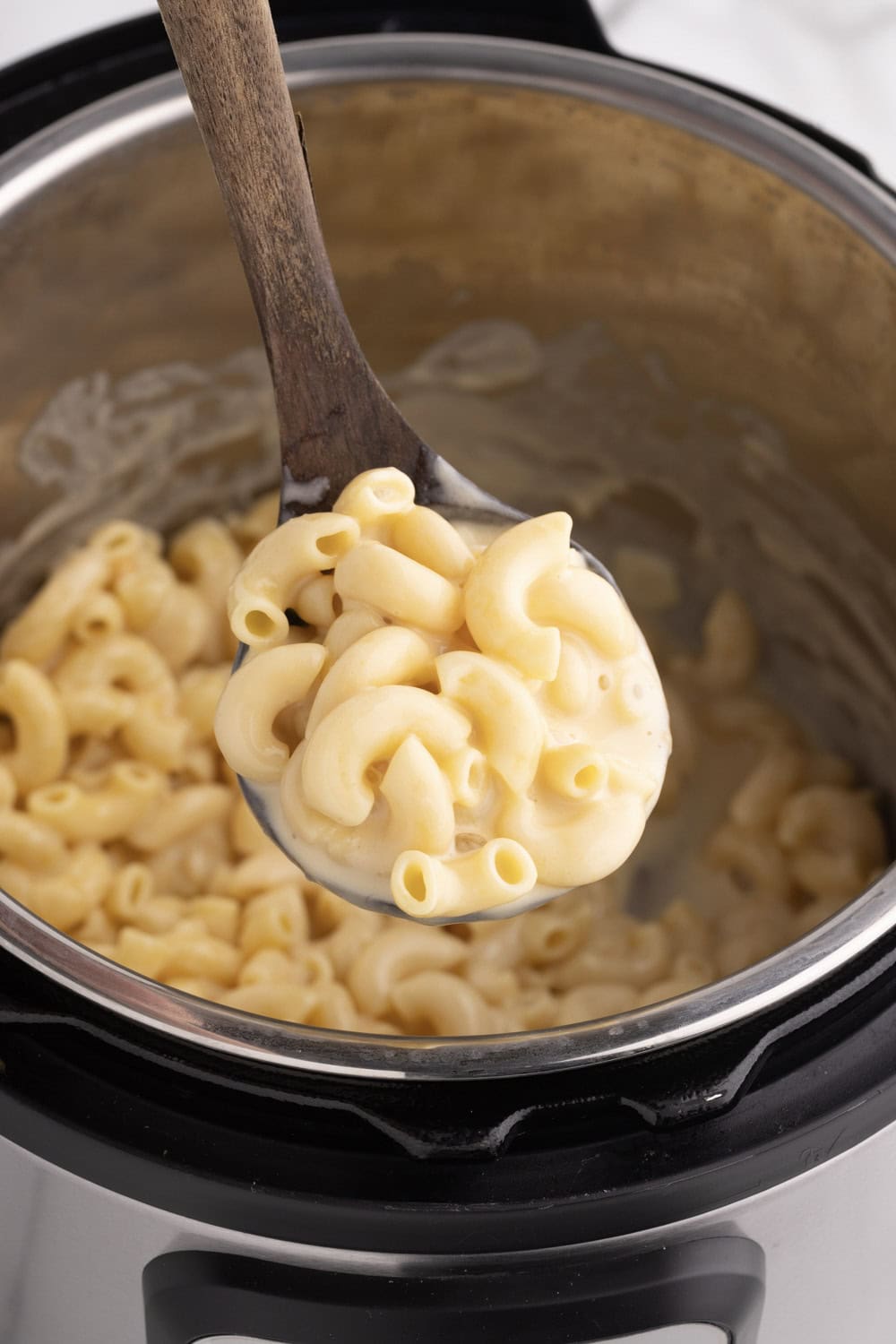 Instant pot macaroni and cheese on a wooden ladle over instant pot
