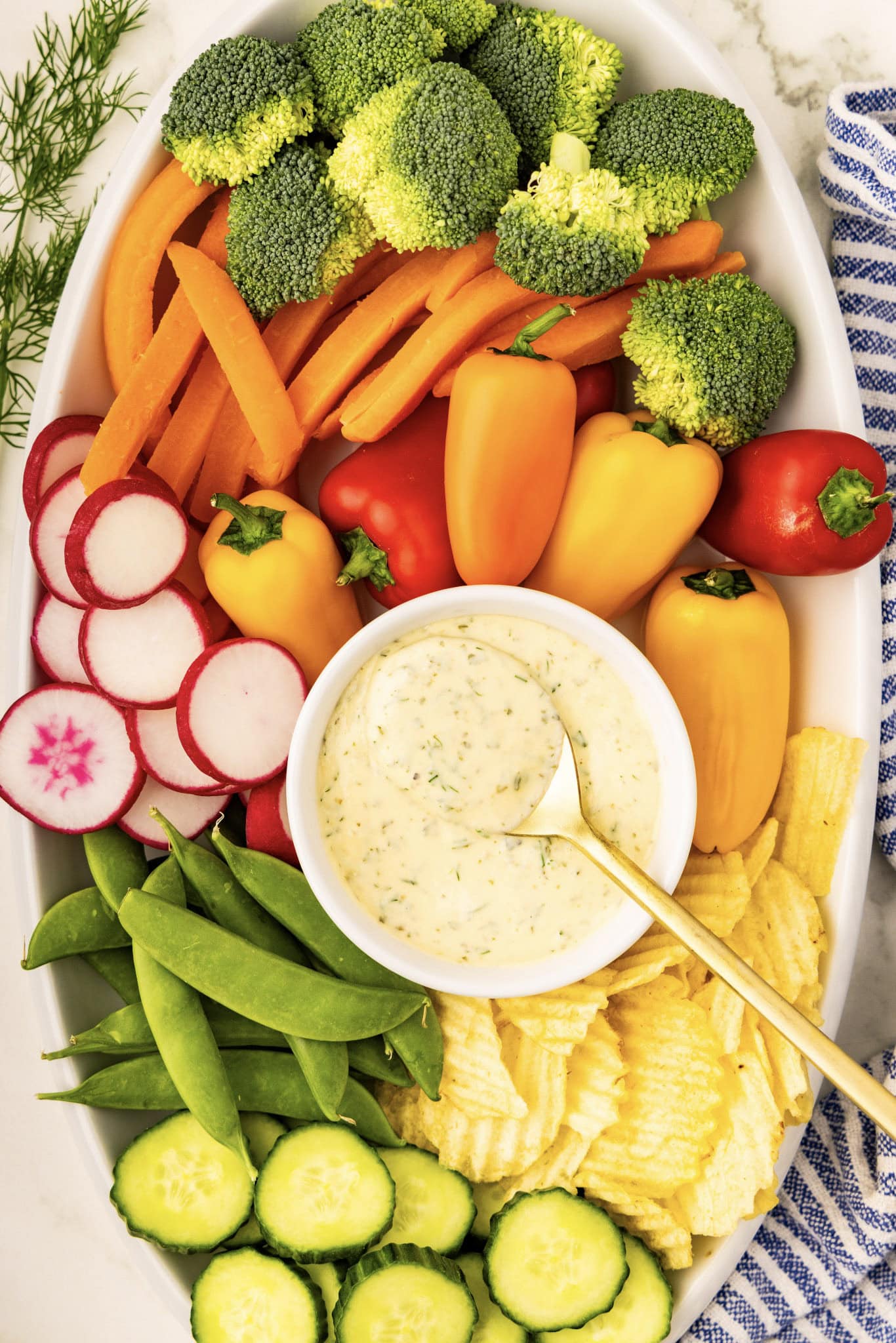A platter of vegetables with dip and a bowl of chips