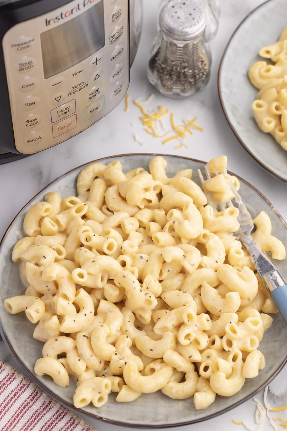 Instant pot macaroni and cheese on gray plate next to instant pot