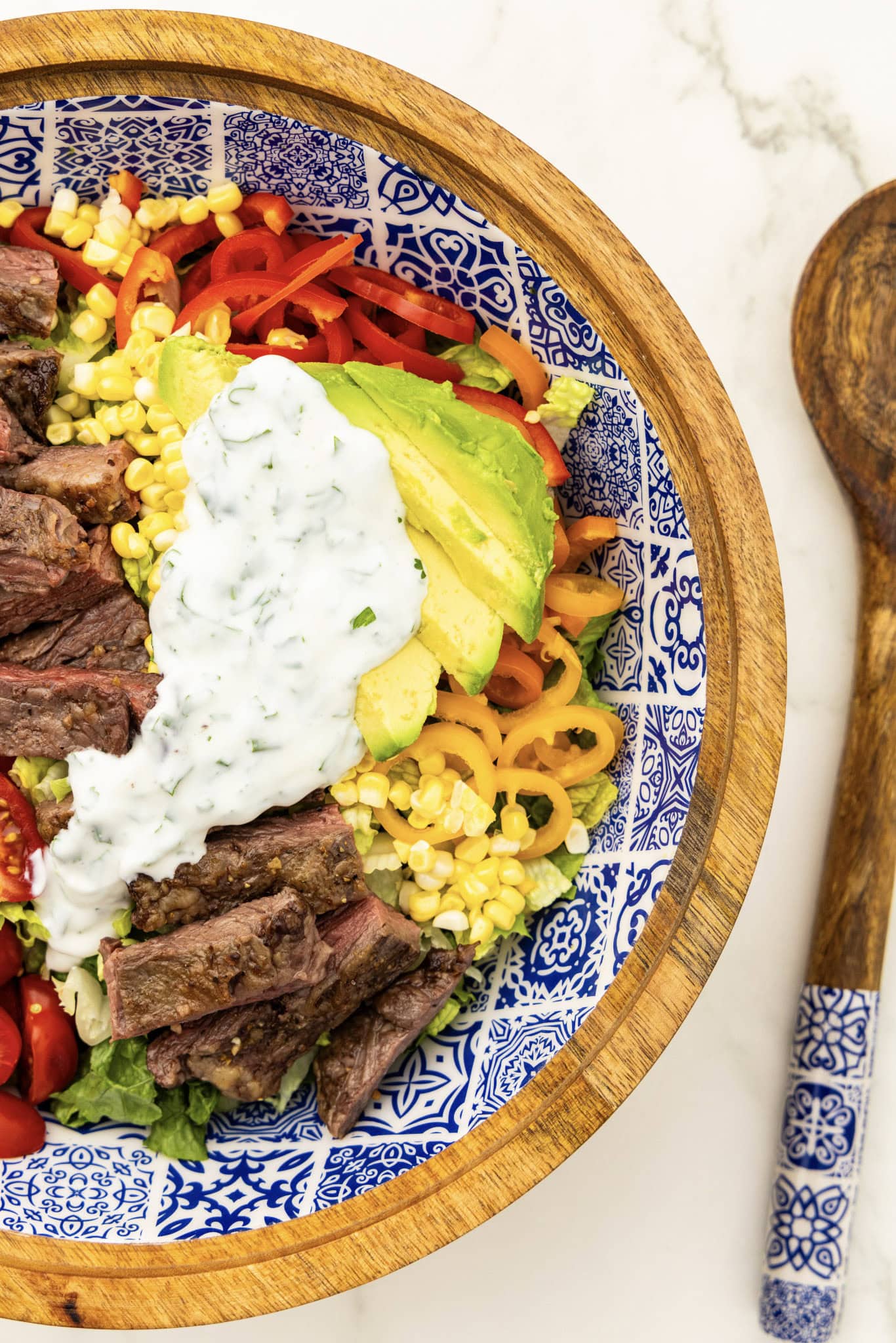 A bowl of steak salad with avocado, corn, tomatoes and homemade ranch