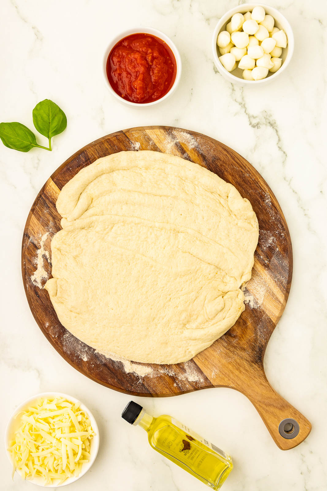 The ingredients for pizza dough are laid out on a wooden board