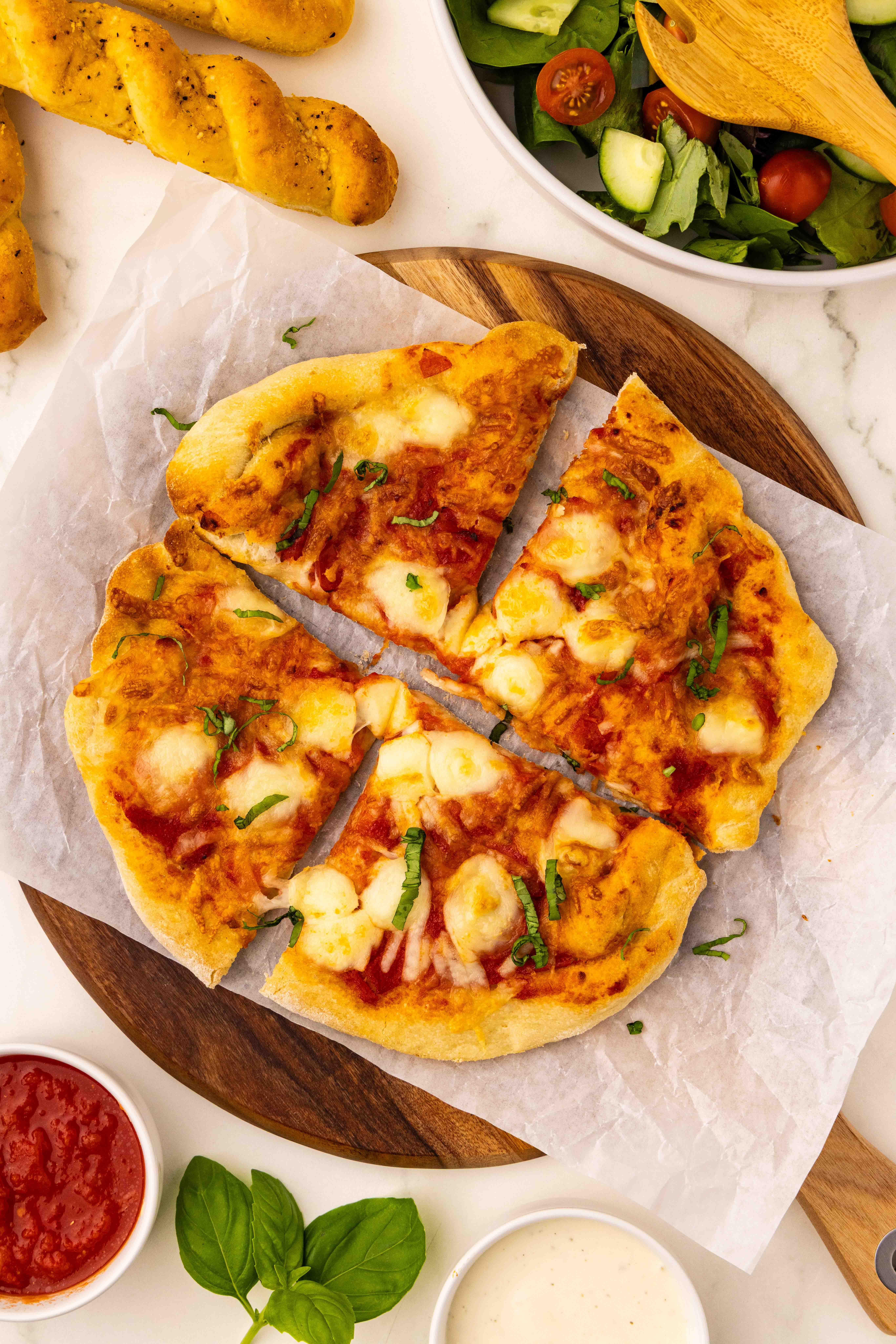 A pizza with cheese and sauce on a cutting board