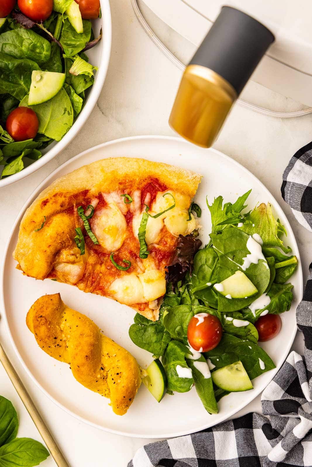 A plate with a slice of pizza and salad on it