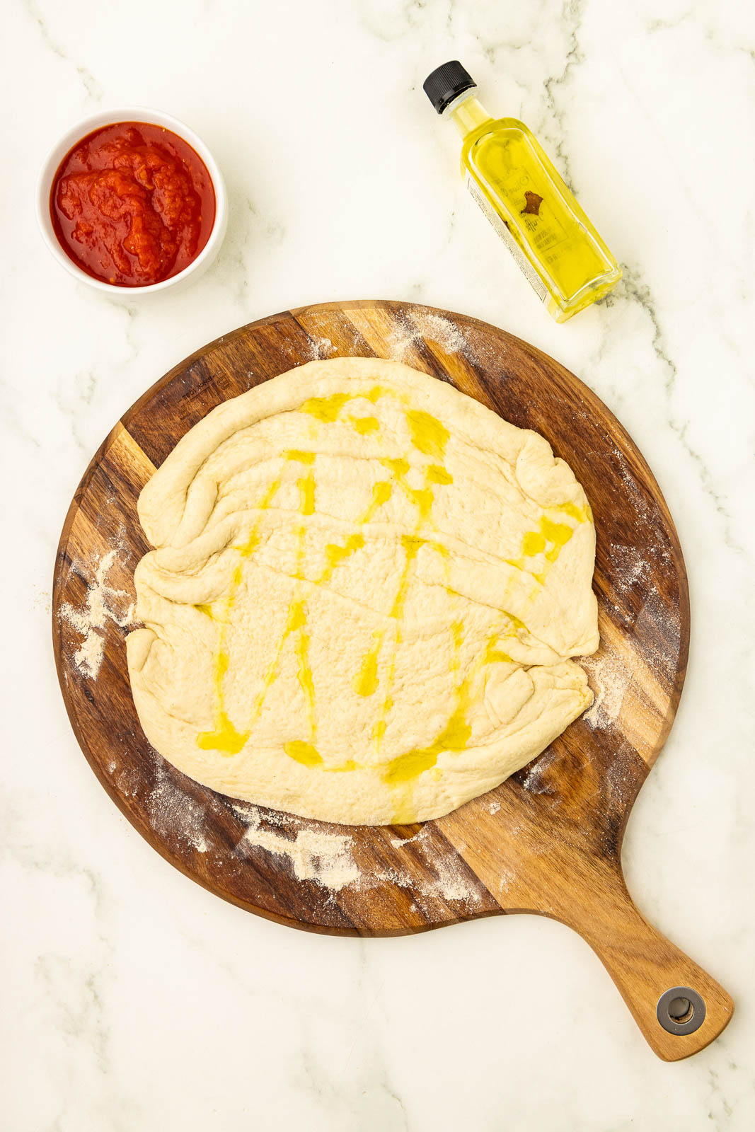 The ingredients for pizza dough are laid out on a wooden board