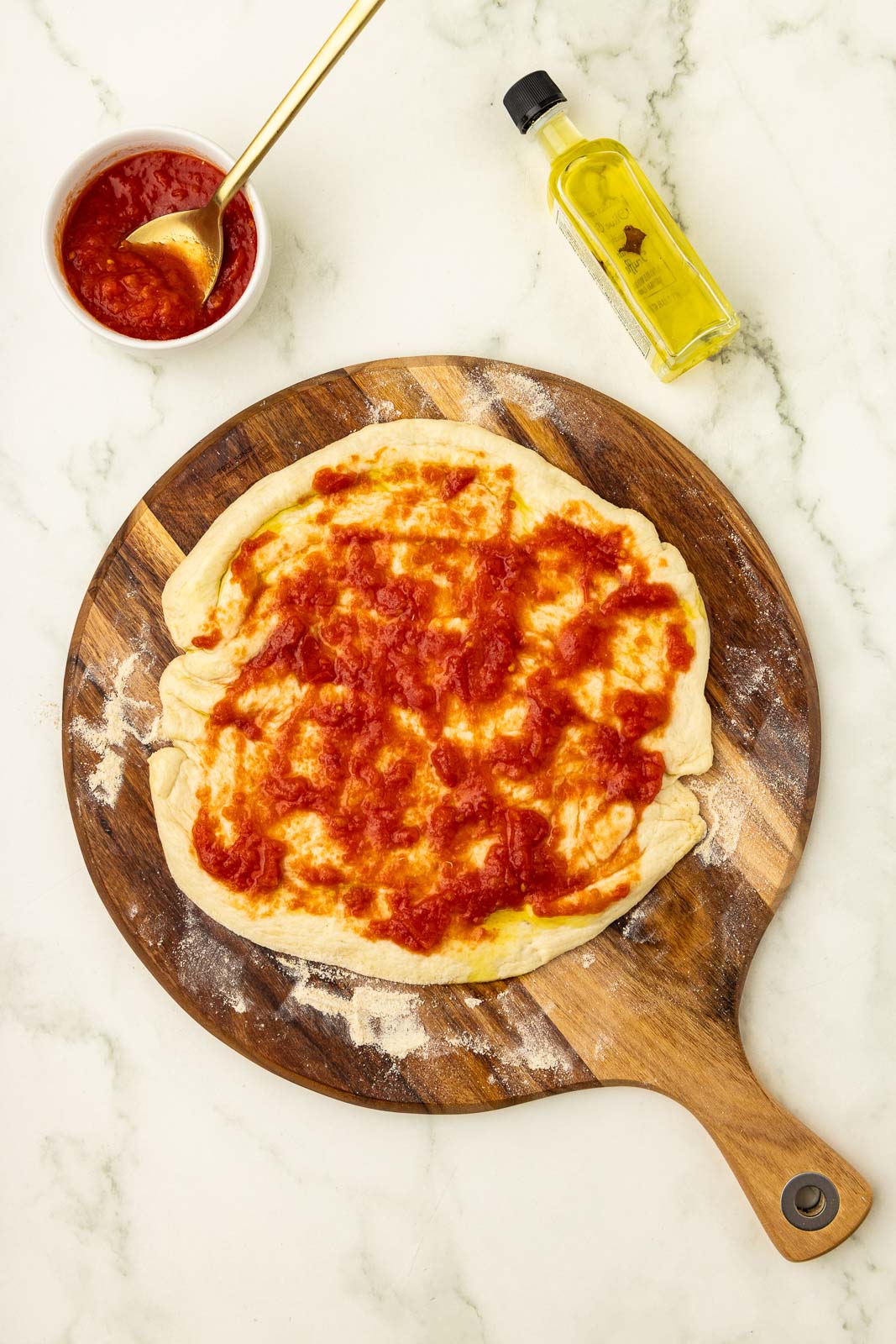 A pizza with tomato sauce on a wooden board