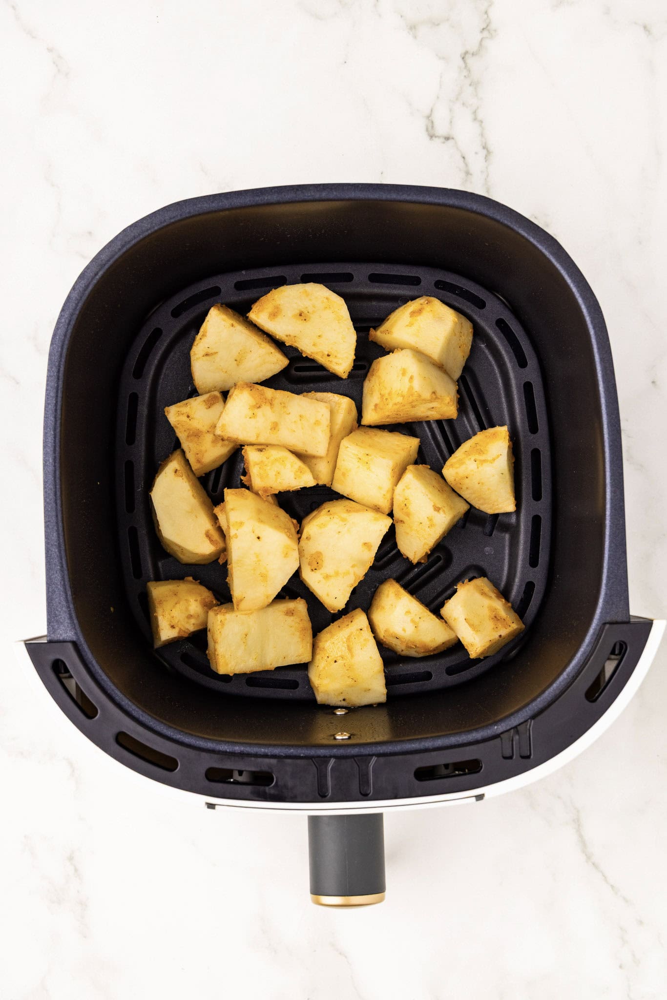 overhead shot of air fryer with cut up potatoes