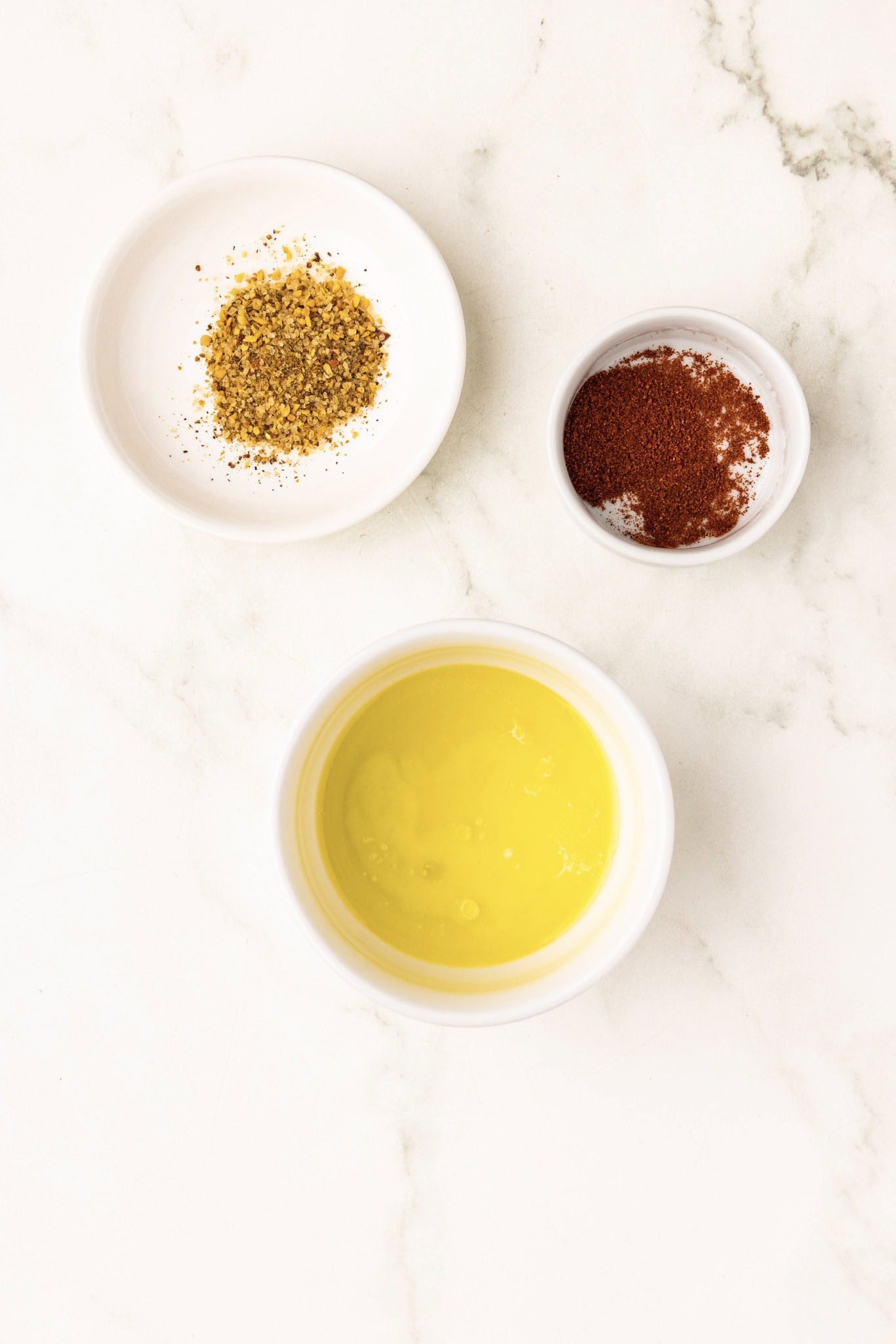 bowls of melted butter, paprika, and steak seasoning