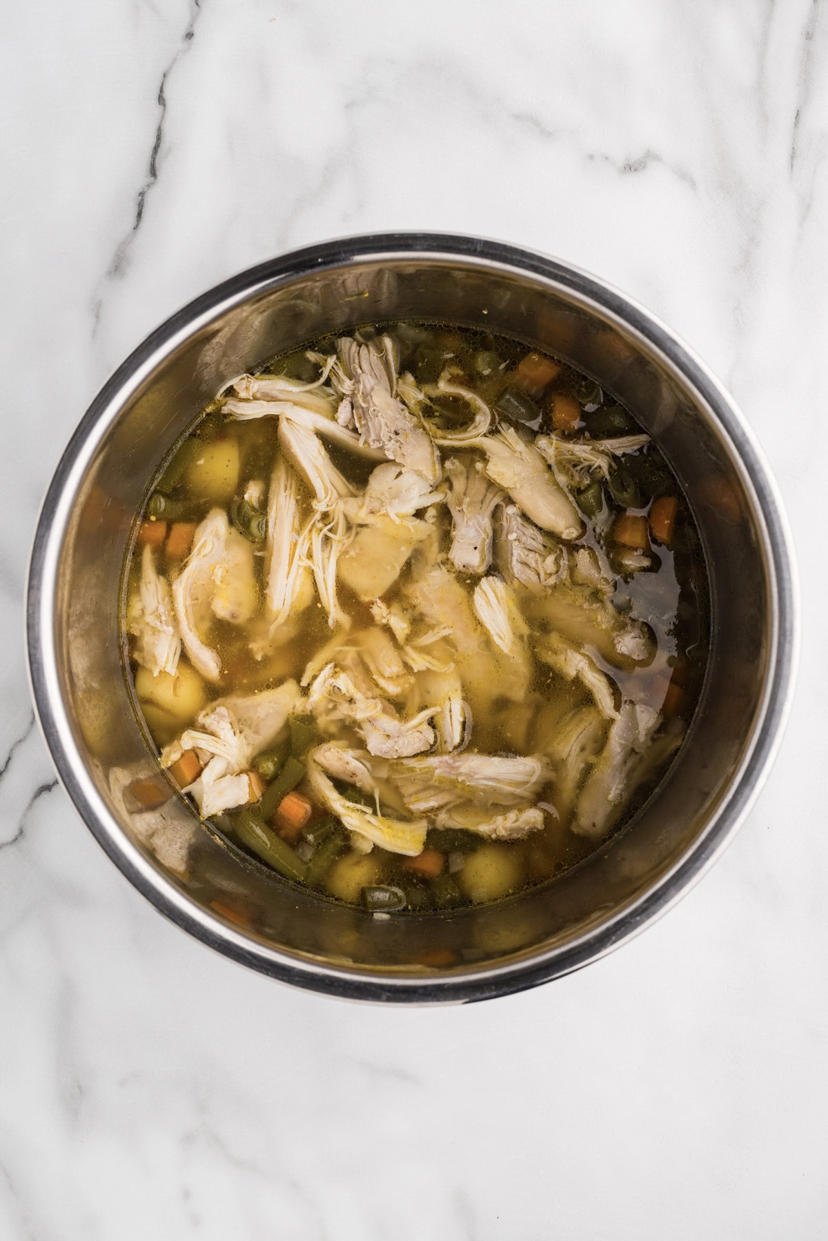 overhead shot of cooked stew with shredded chicken added
