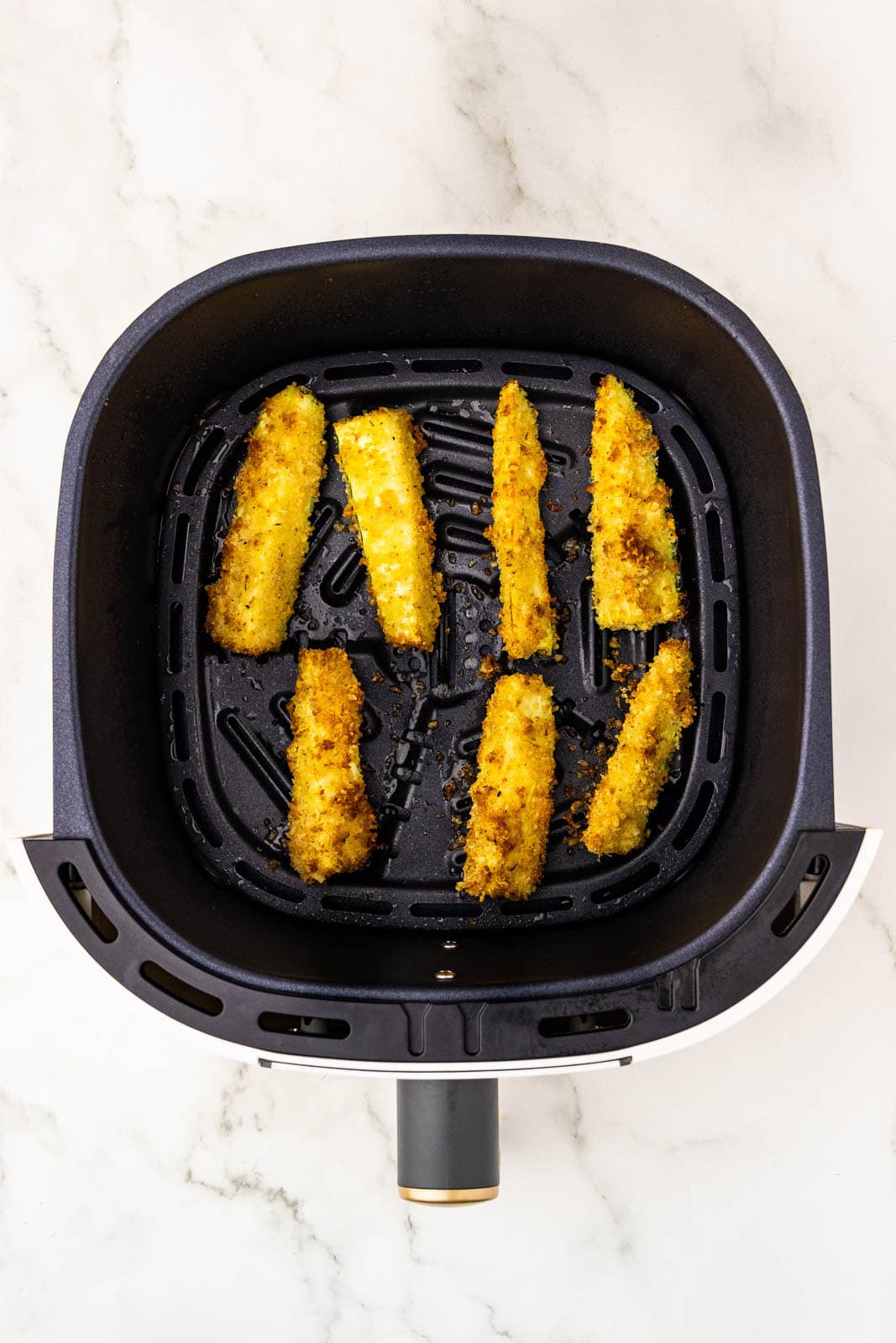 overhead view of air fryer with air fried zucchini slices