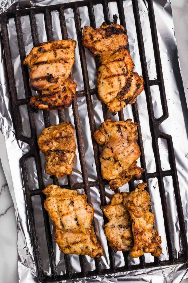 black grill grate with grilled chicken thighs