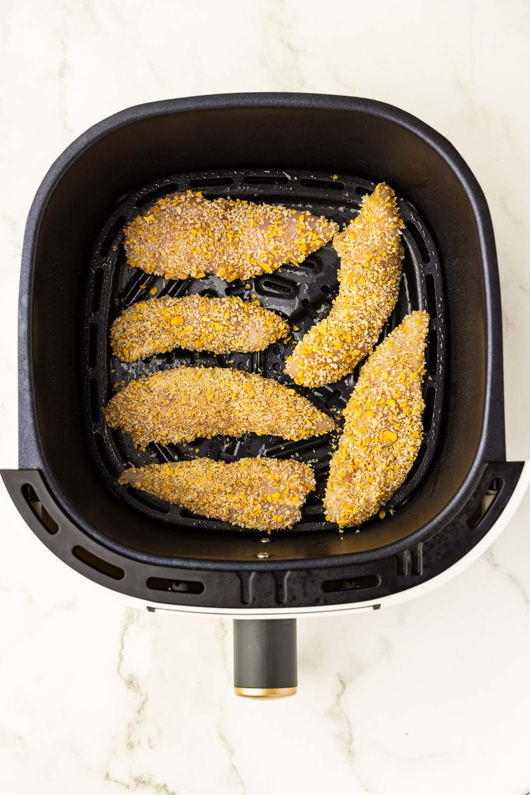 overhead view of black air fryer 6 coated chicken tenders