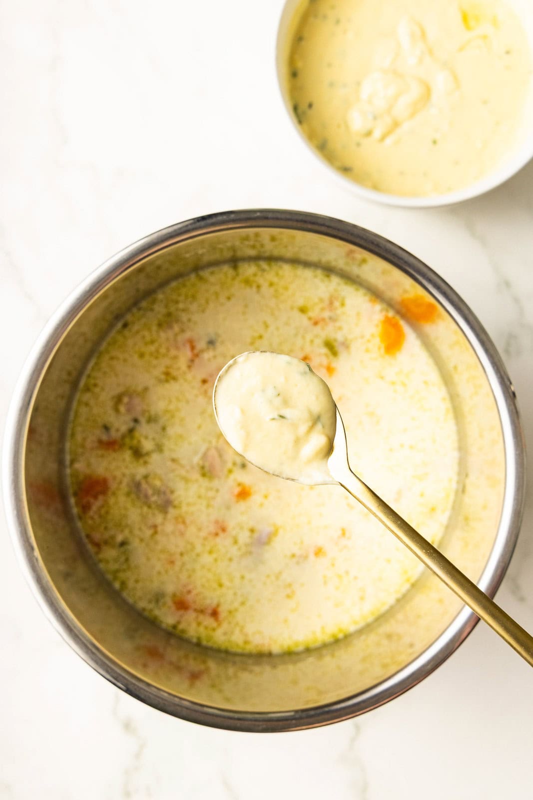 overhead view of instant pot with cooked chicken with gold spoon of bread mixture over it, with bowl of bread mixture in background