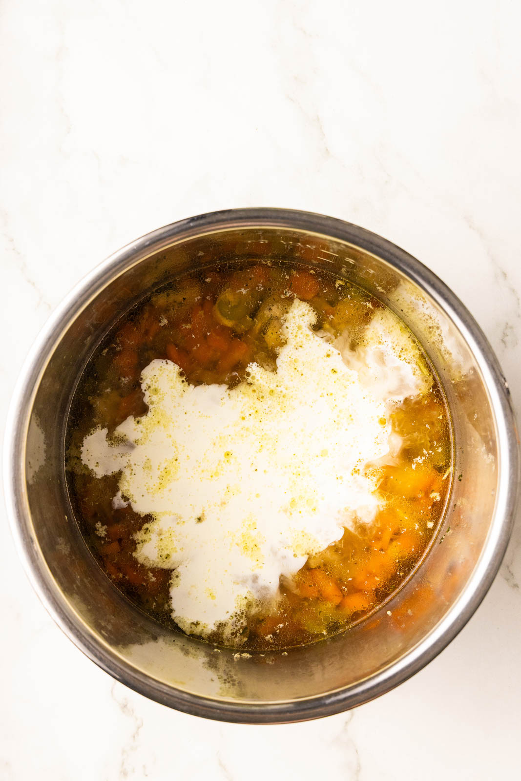 overhead view of instant pot containing diced chicken, carrots and celery, seasoning, chicken broth, cornstarch and cream mixture