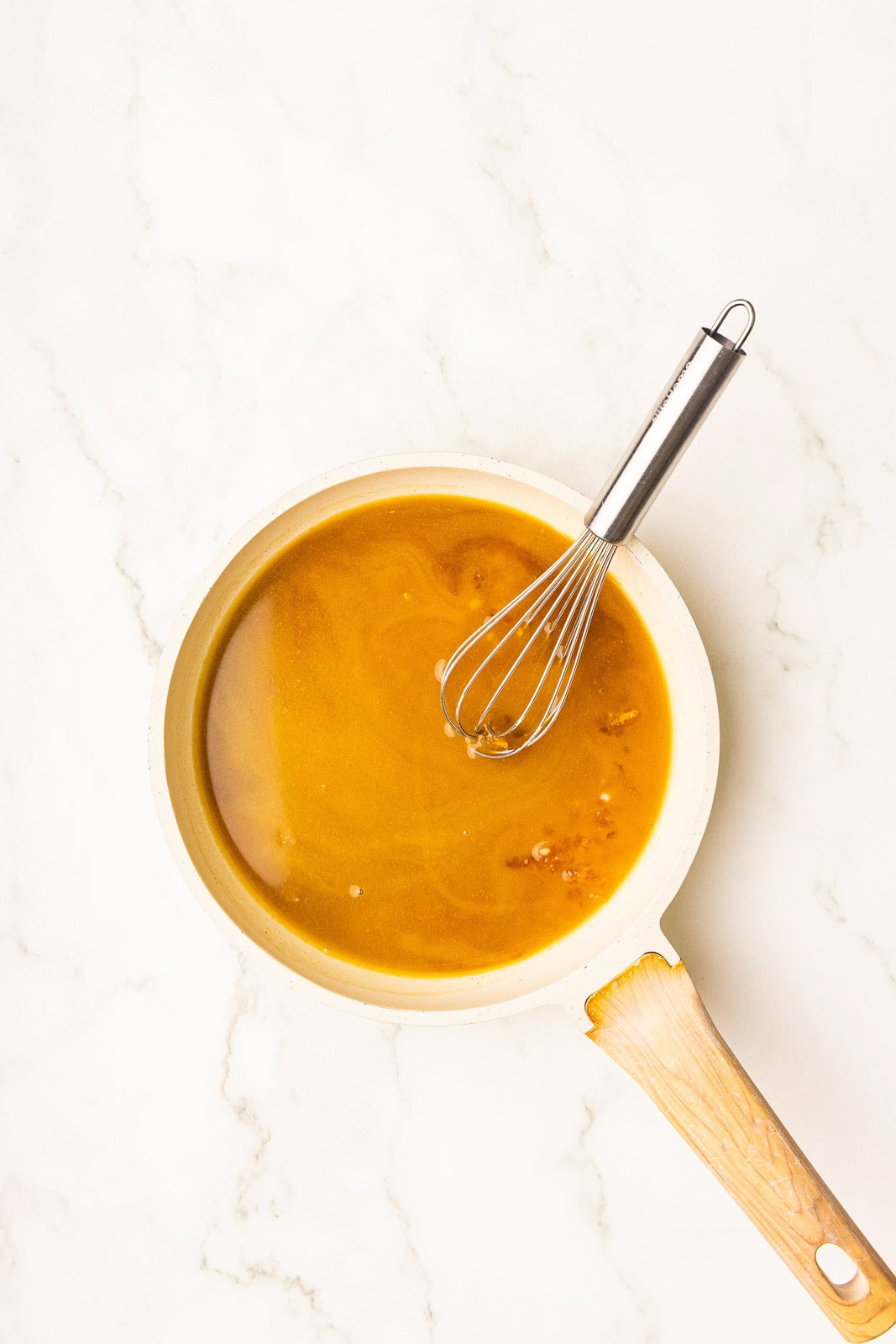 skillet with orange mixture with silver whisk