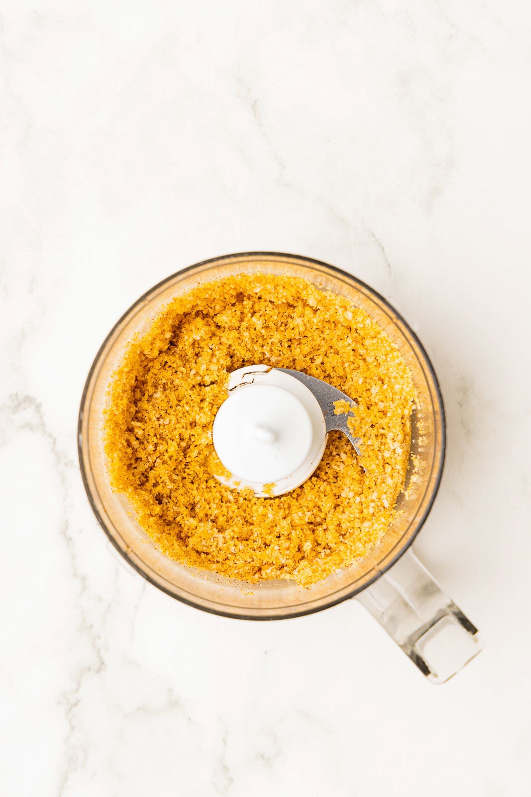 overhead view of small food processor containing potato chips, panko and seasonings mixed together