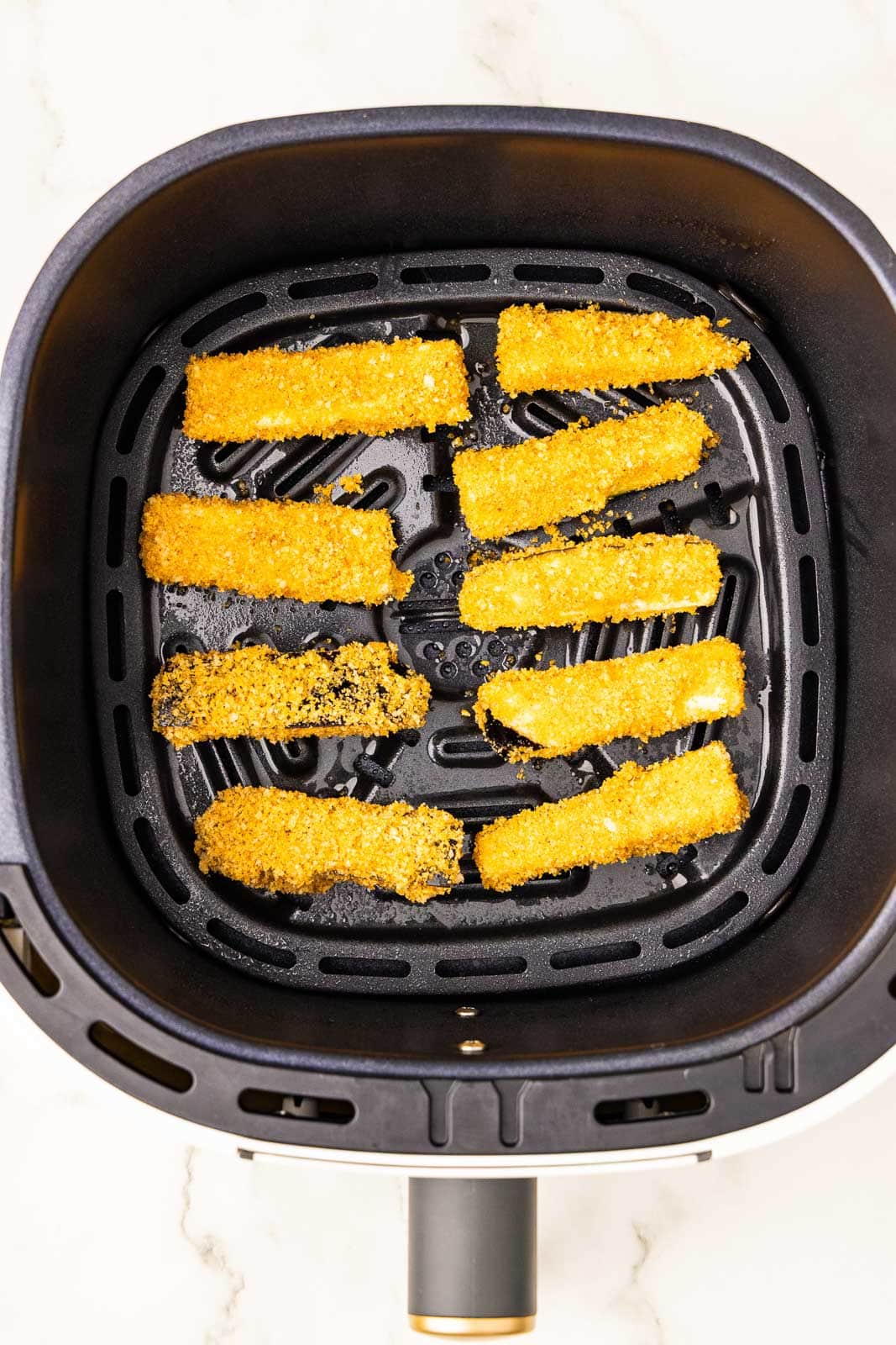 overhead view of air fryer with 10 covered eggplant sticks