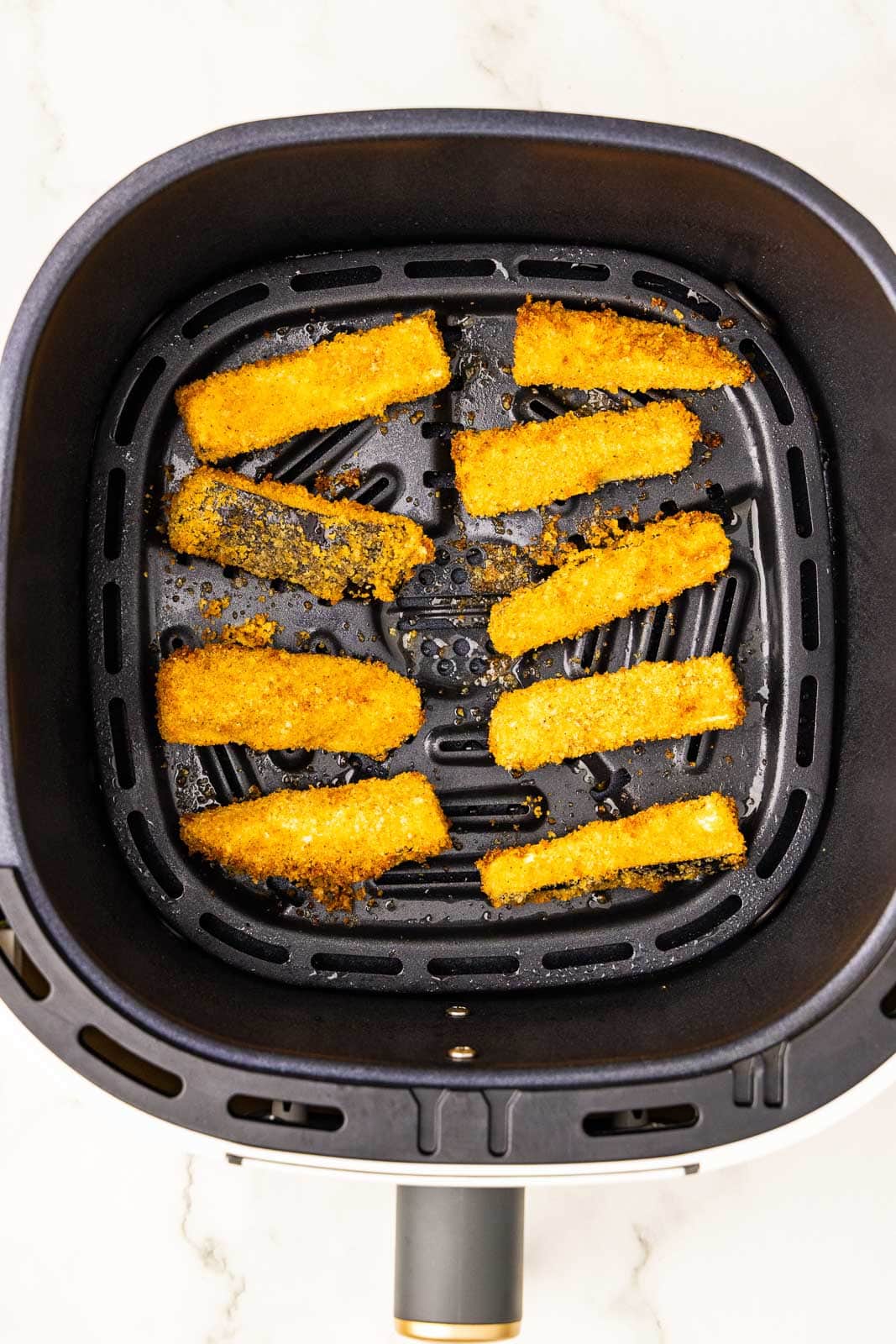 overhead view of air fryer containing 10 air fried eggplant sticks