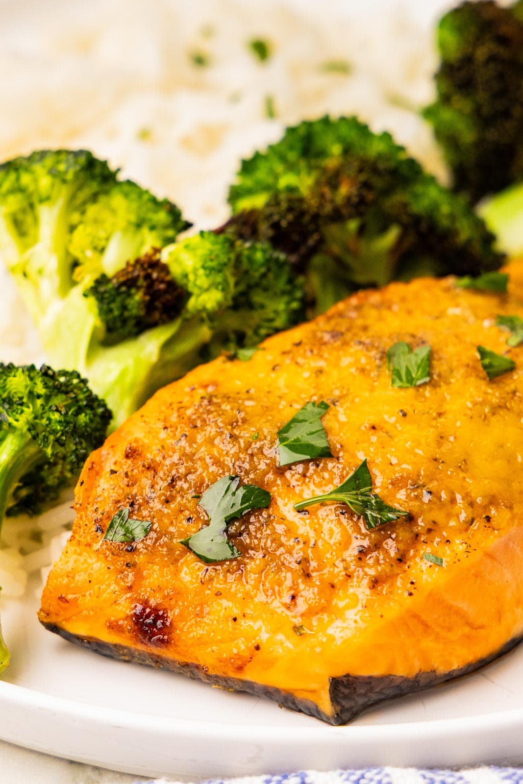 closeup of cooked air fryer salmon on a plate with broccoli in background