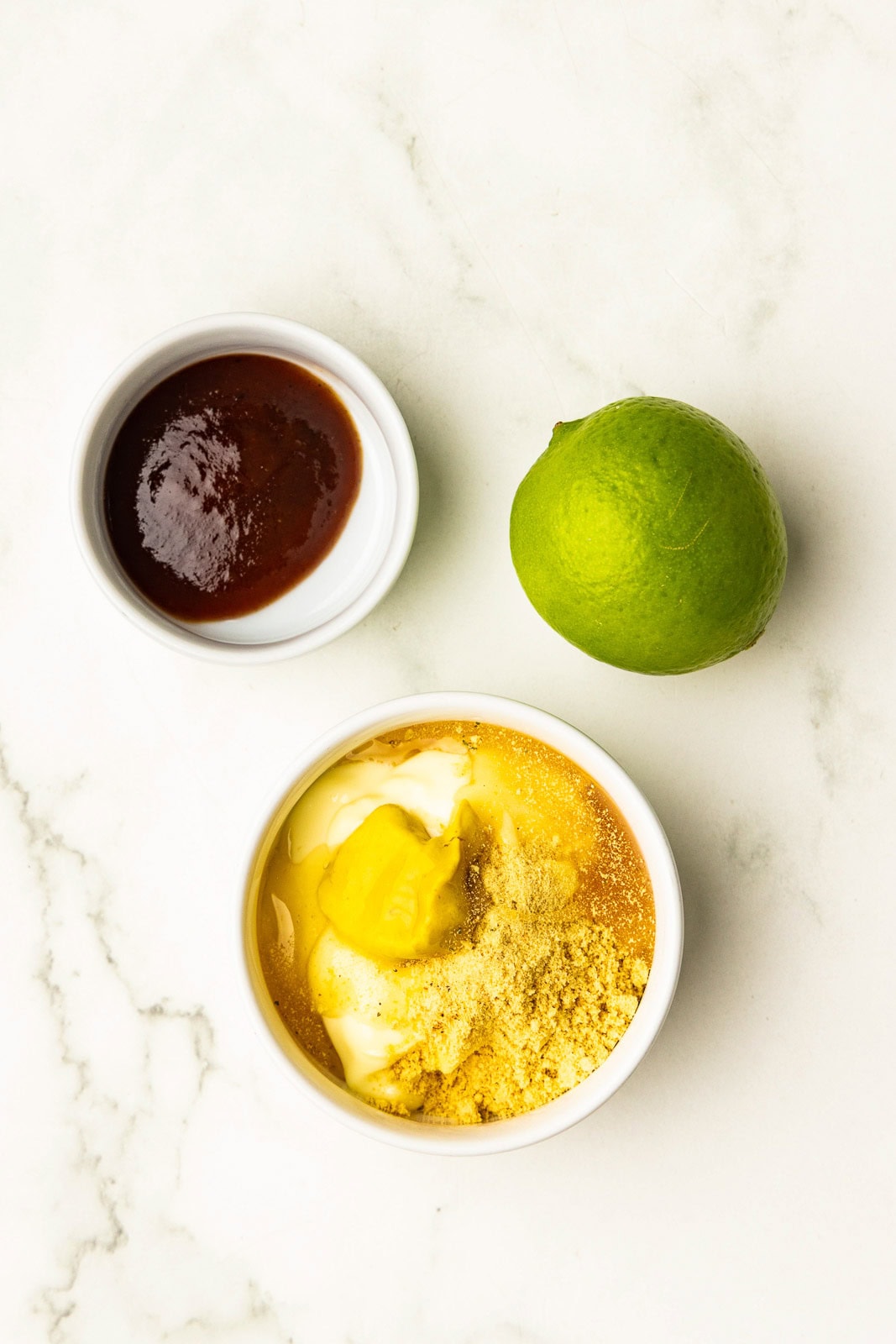 2 white bowls with bbq sauce and mayo mixture, alongside a lime
