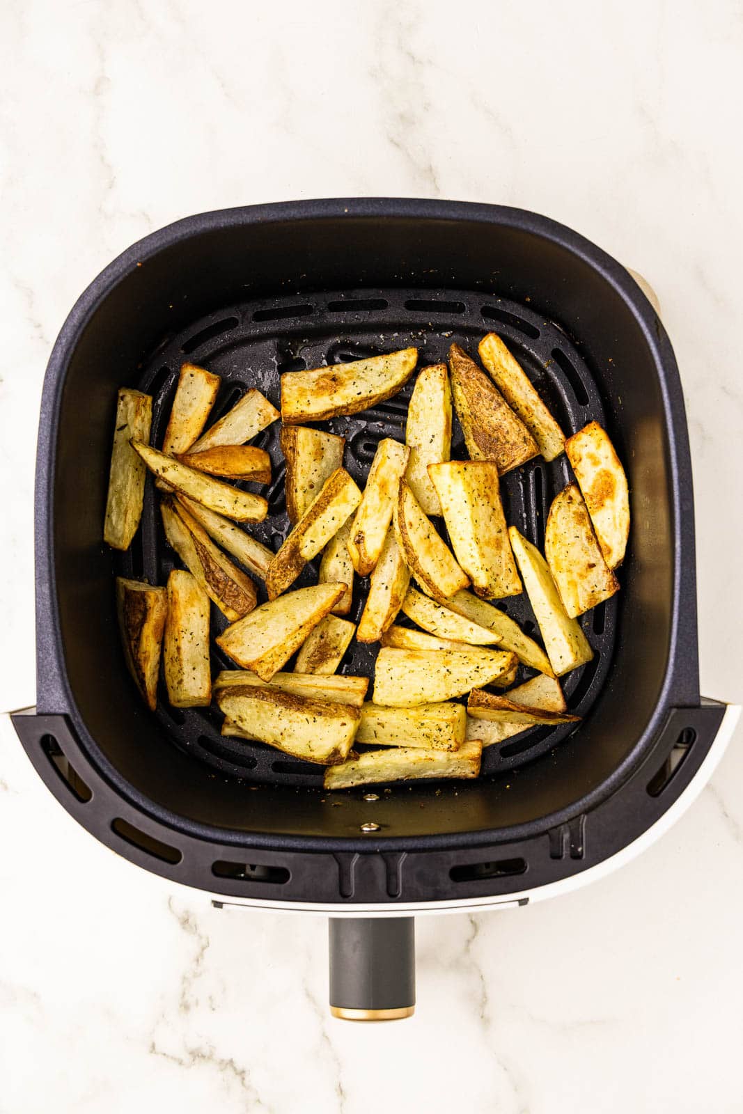 overhead view of black air fryer containing air fried potato slices