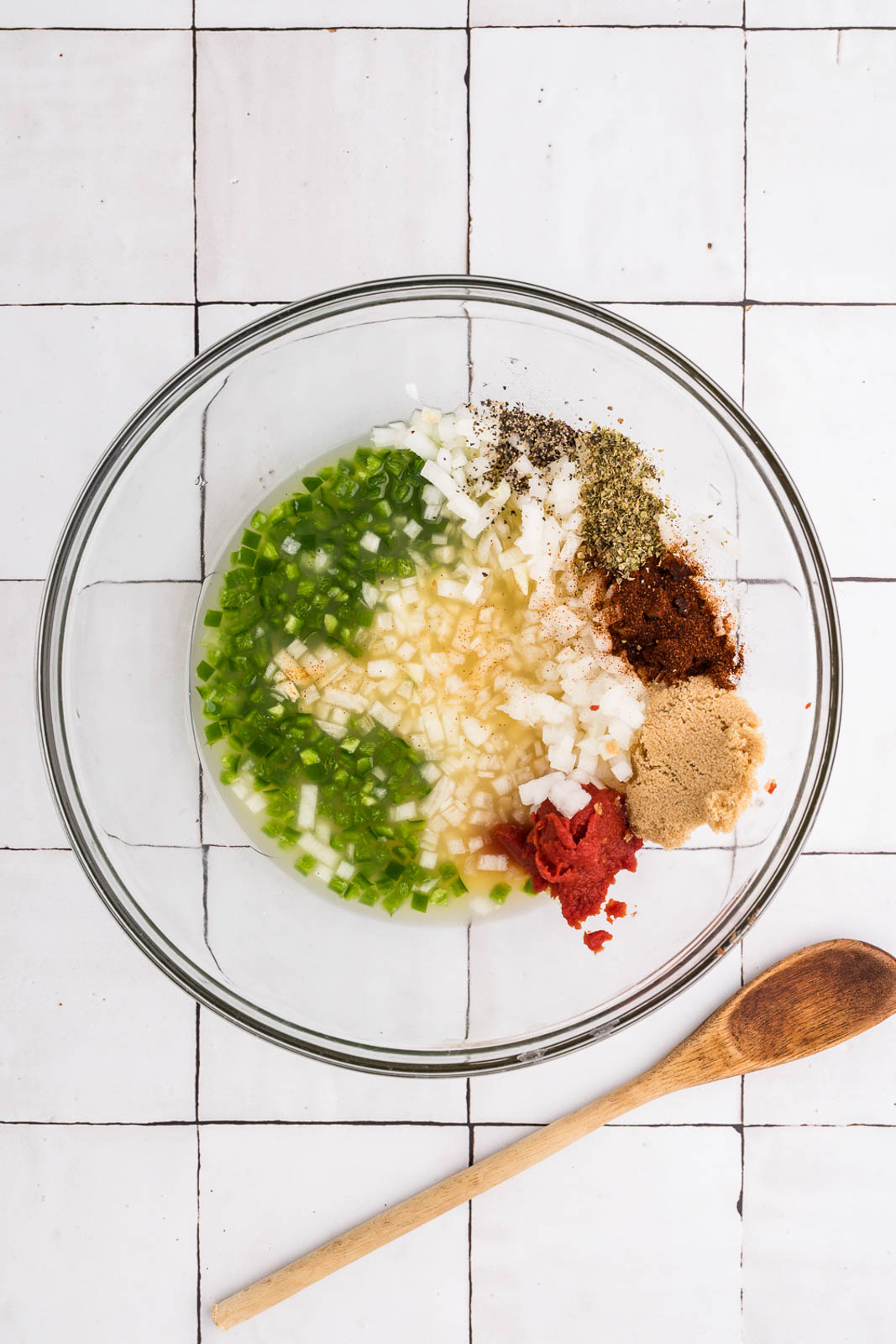 clear bowl of ingredients, except for pork, with wooden spoon on side