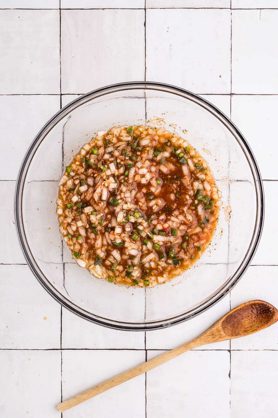 clear bowl of ingredients, except for pork, with wooden spoon on side