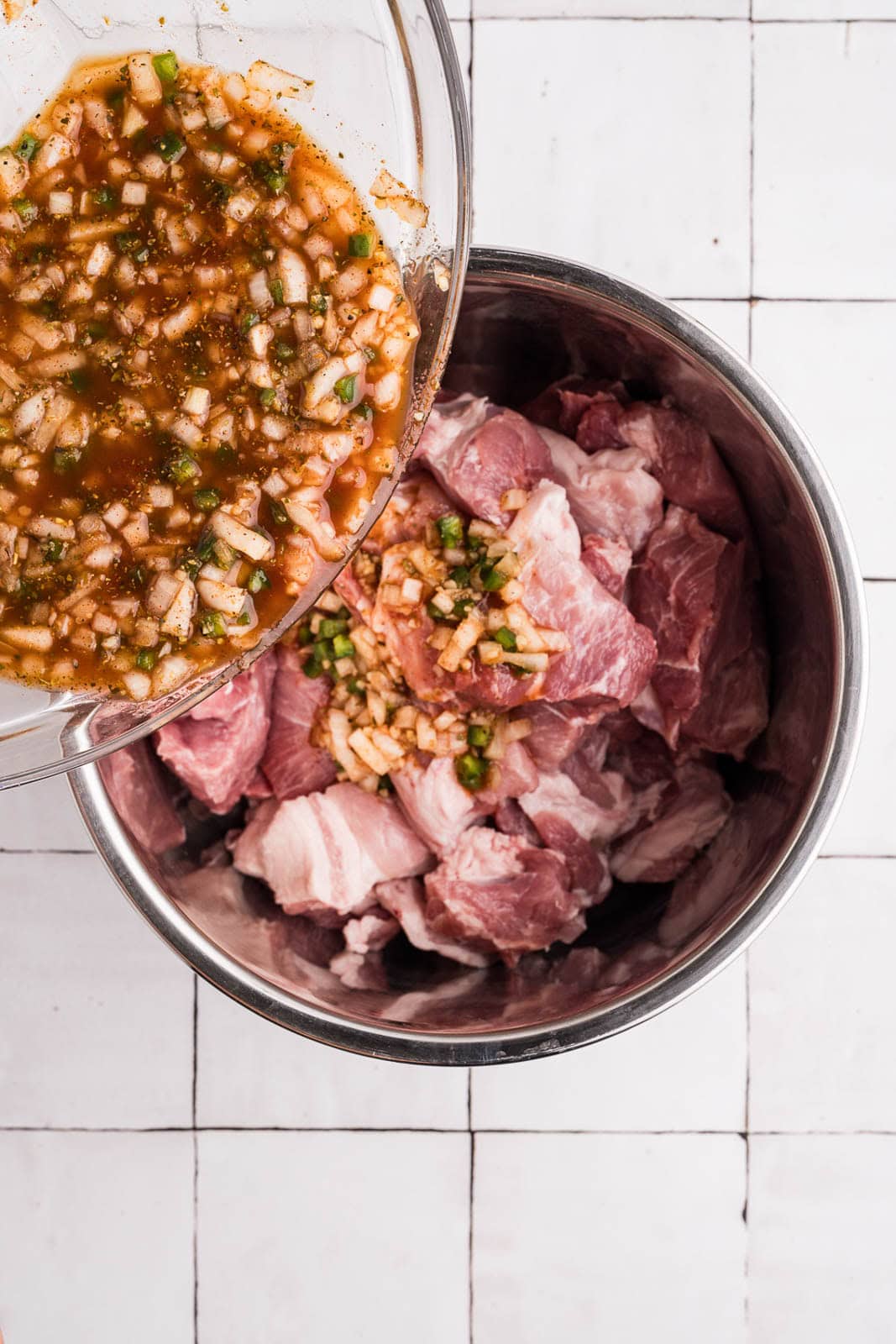 cubed pork in instant pot with bowl of other ingredients being poured into the pot