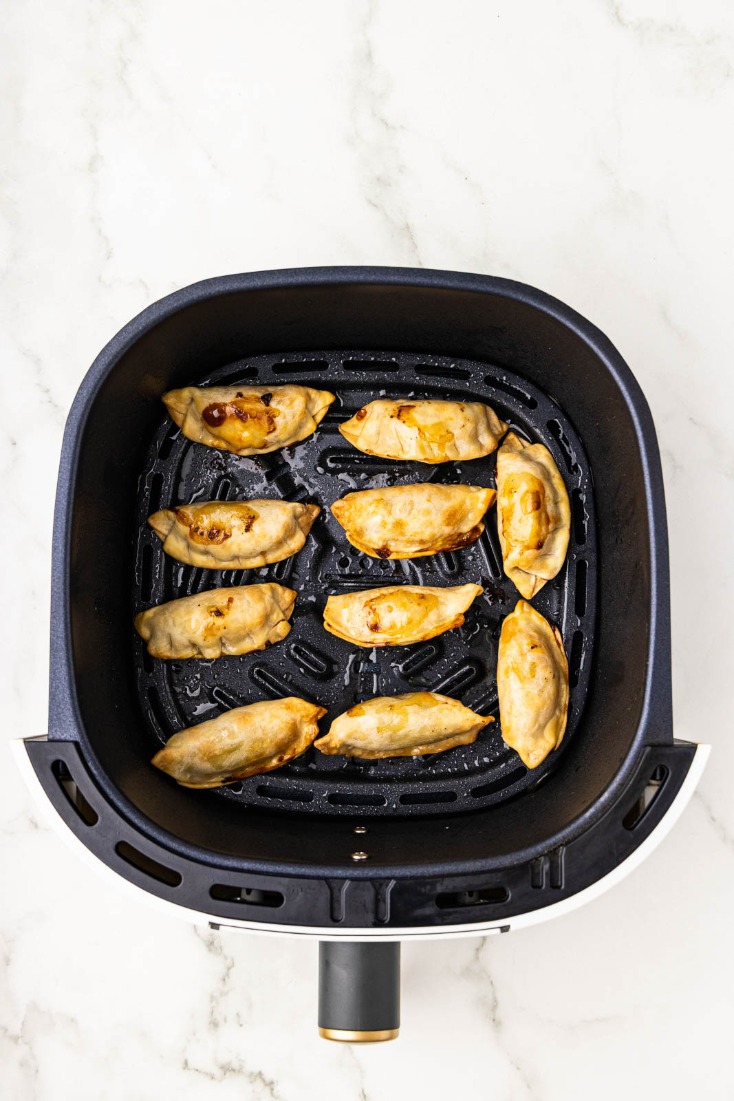 overhead view of black air fryer with 10 air fried pot stickers