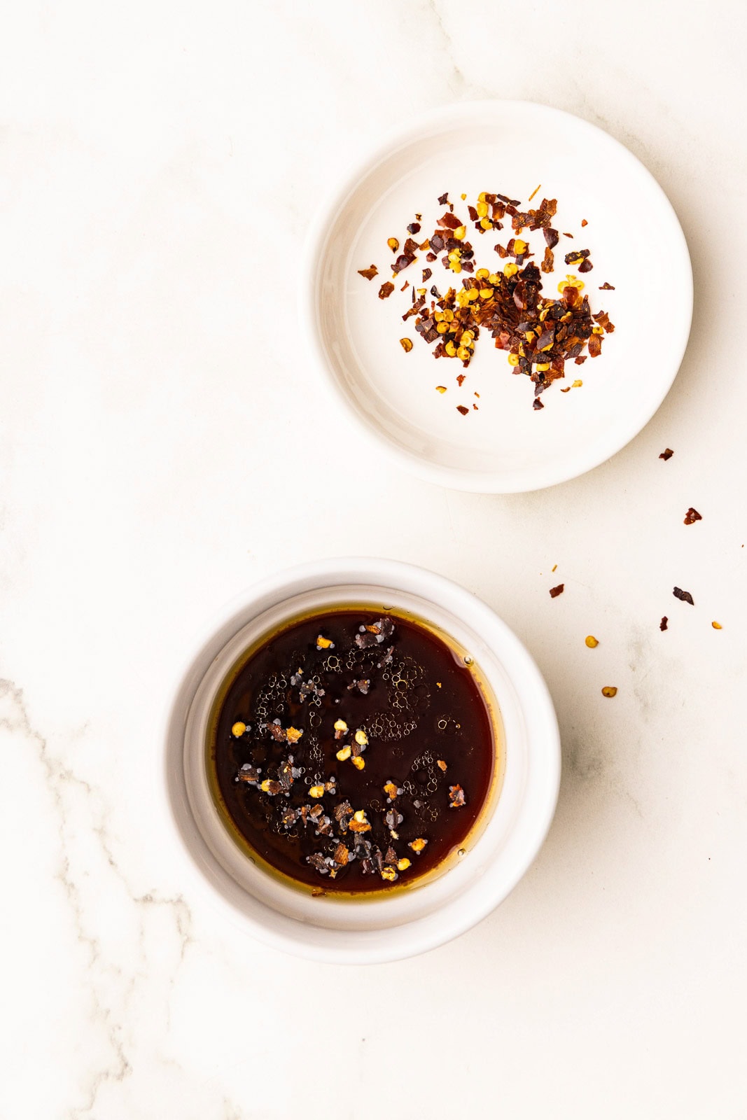 two white bowls, one with finished dip sauce and one with chili flakes